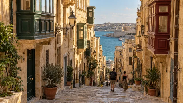 A limestone street in Valletta descends toward the Grand Harbour